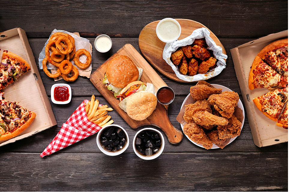 Spread of pizza, burgers, wings, onion rings and fries from 80's Pizza & Grill